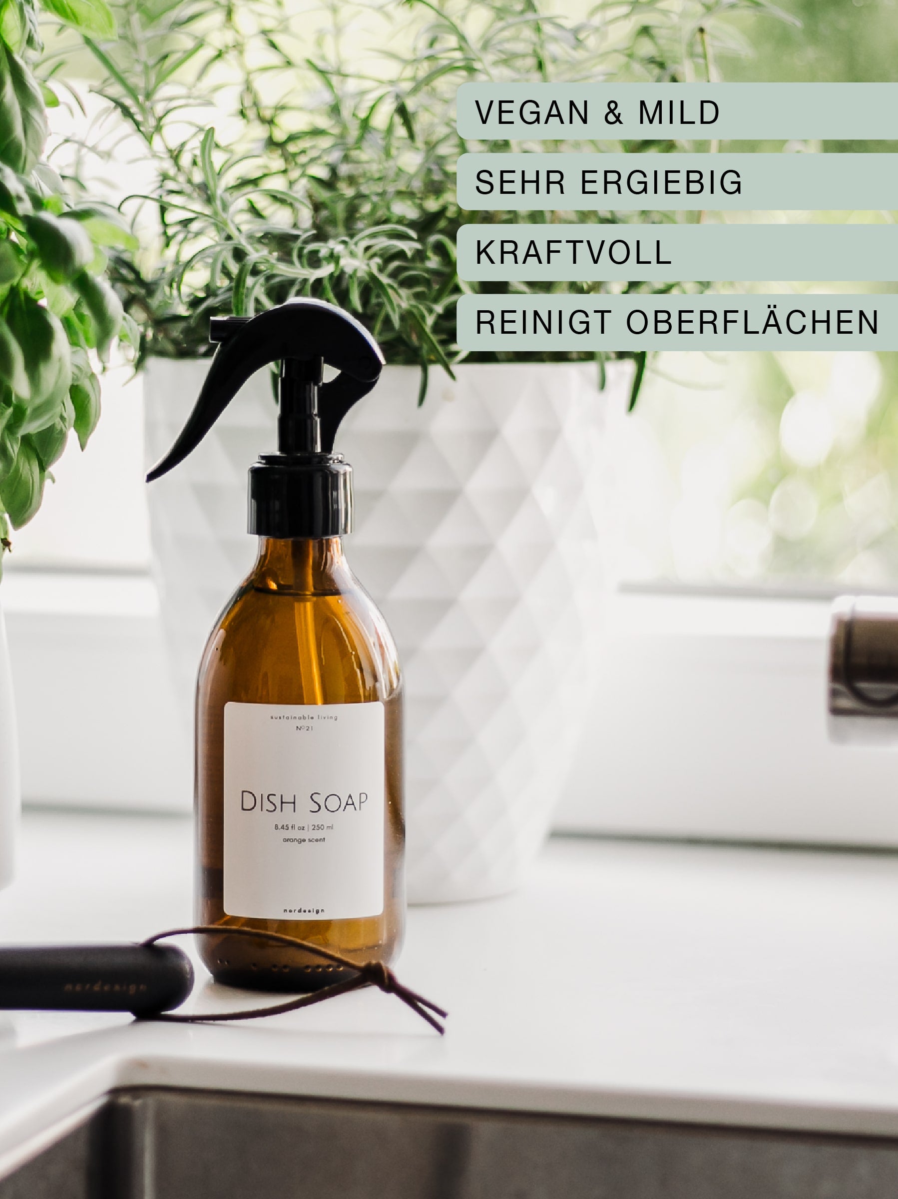 Spülmittel mit Sprühaufsatz in wiederauffüllbarer Glasflasche in einer weißen Küche